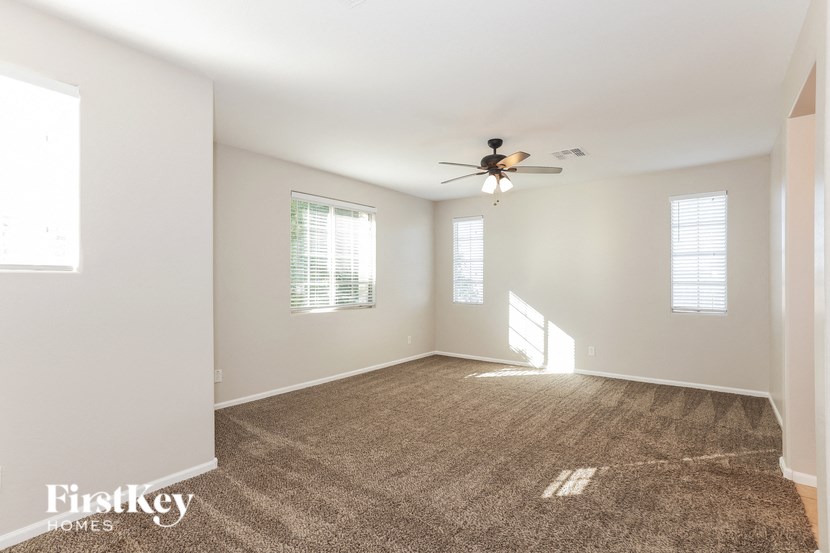 an empty living room with a ceiling fan and carpet