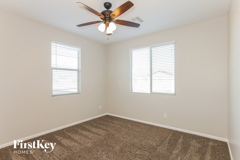 a bedroom with a ceiling fan and two windows
