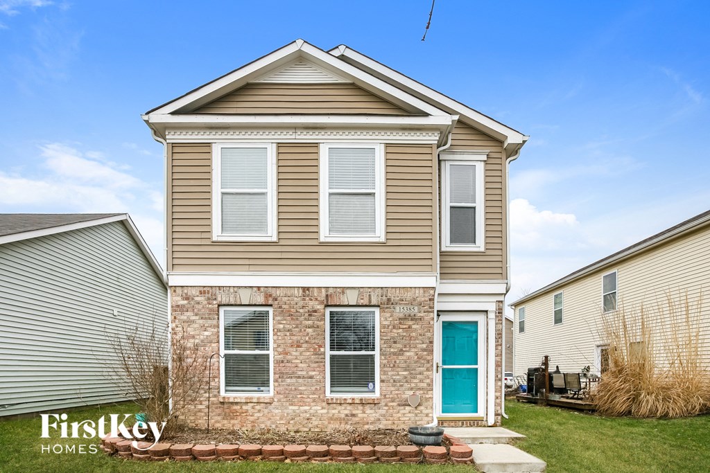 a tan house with a blue door on a lawn