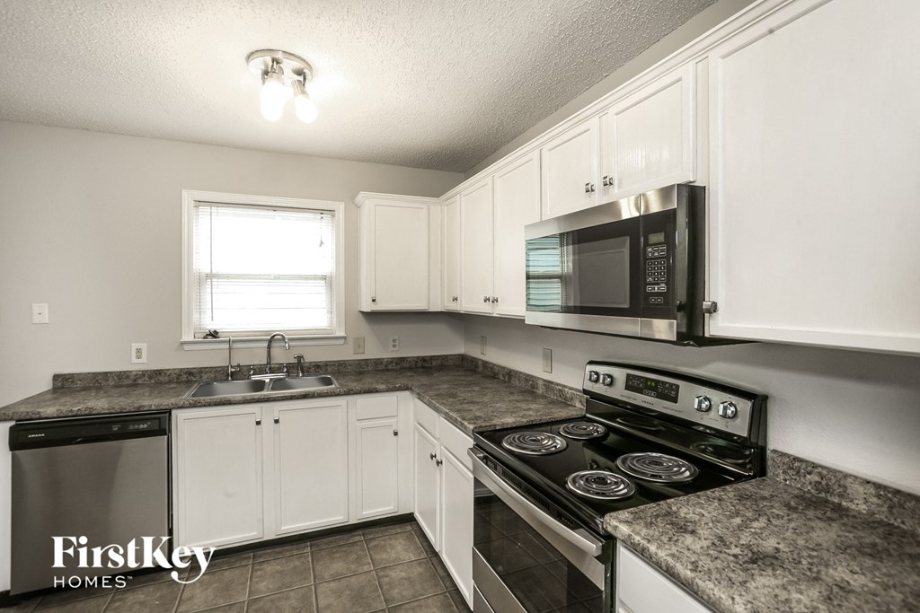 a kitchen with white cabinets and granite counter tops