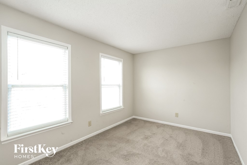 a bedroom with a carpeted floor and two windows