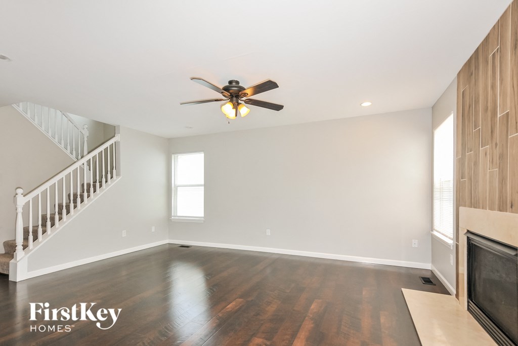 an empty living room with a ceiling fan and a staircase