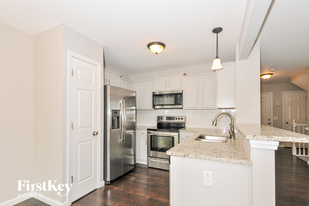a white kitchen with stainless steel appliances and a marble counter top