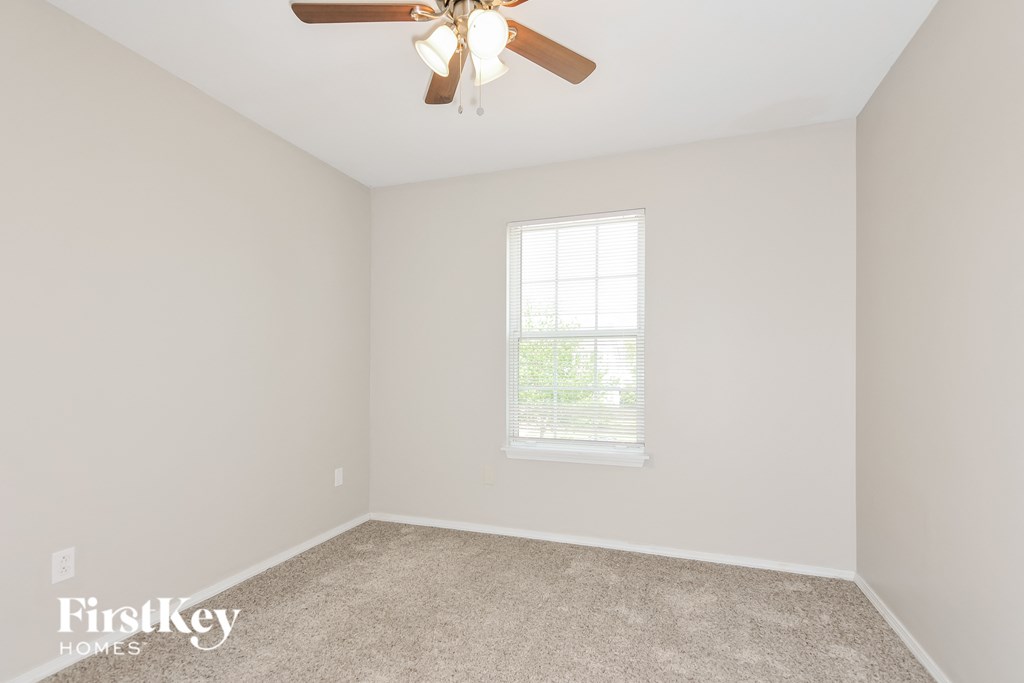 a bedroom with white walls and a ceiling fan