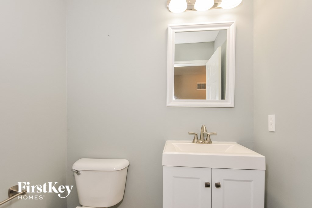 a bathroom with a toilet sink and mirror and a mirror over a sink and toilet