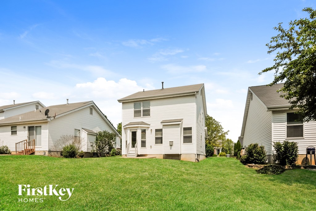 two white houses on a green lawn with a blue sky