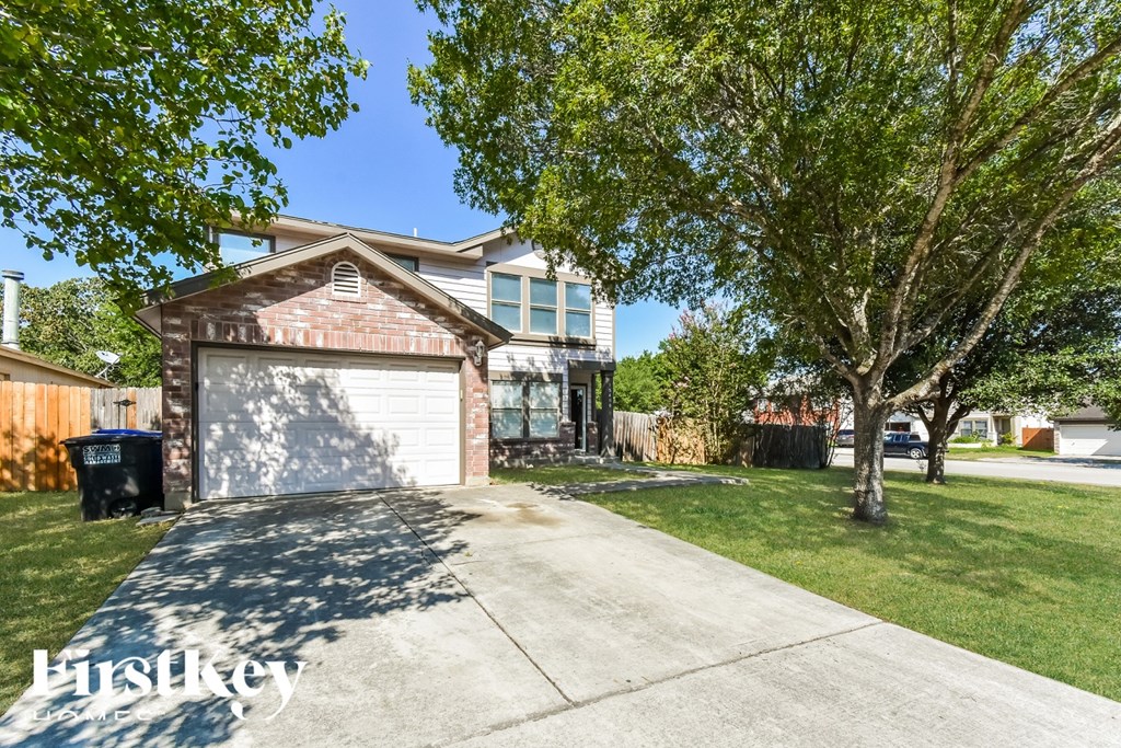 A house with a garage and a tree in front.