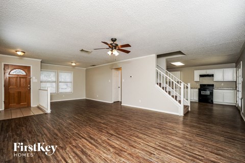 A spacious room with wood flooring and a ceiling fan.