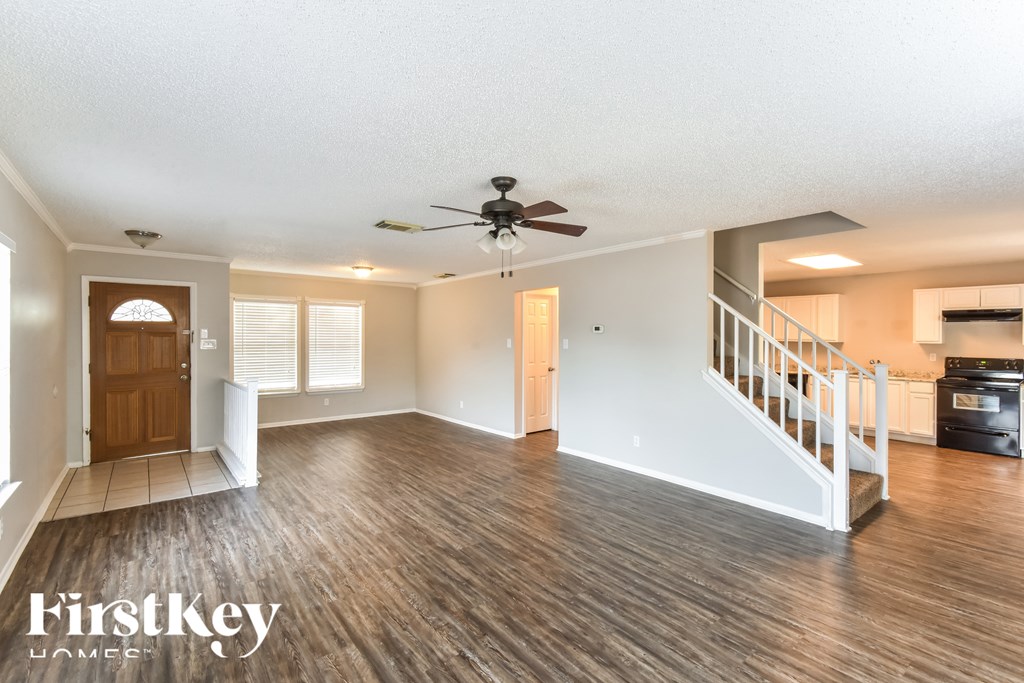 A spacious room with wood flooring and a ceiling fan.