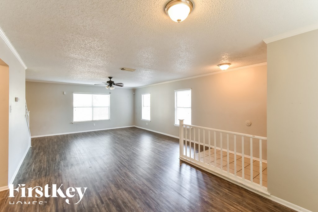 A spacious room with wood flooring and a ceiling fan.