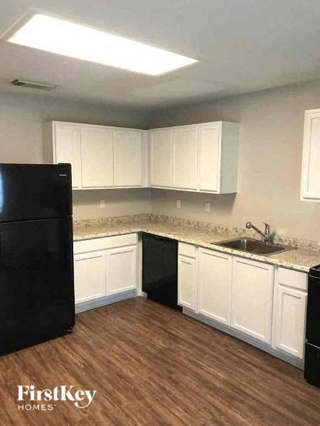 A kitchen with white cabinets and a black refrigerator.