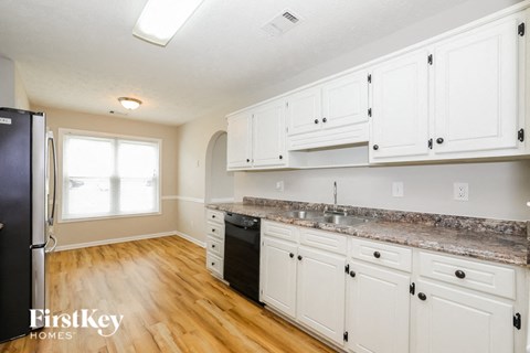 a kitchen with white cabinets and a wood floor and a refrigerator