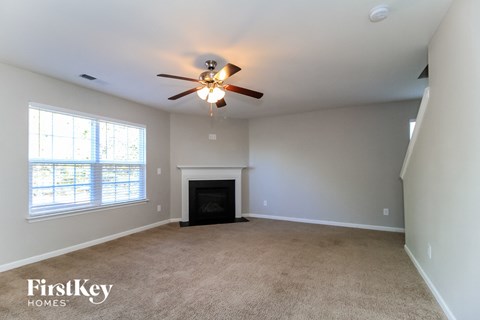 A spacious room with a fireplace and a ceiling fan.