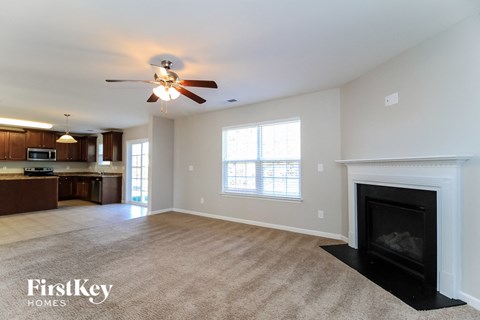 A spacious living room with a fireplace and a ceiling fan.