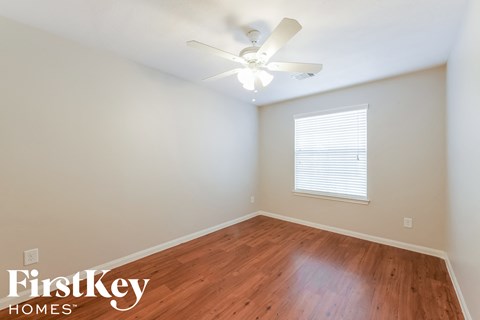 a bedroom with wood flooring and a ceiling fan