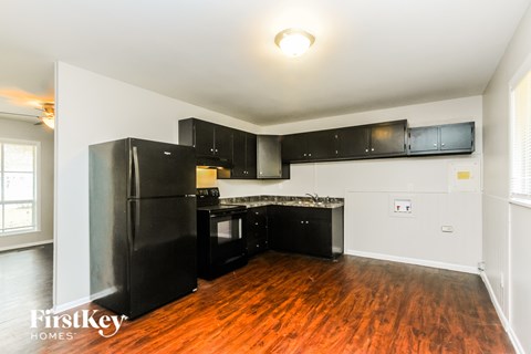 A kitchen with black appliances and wooden floors.