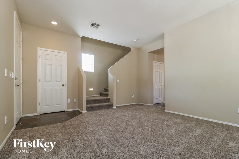 an empty living room with two doors and a carpeted staircase