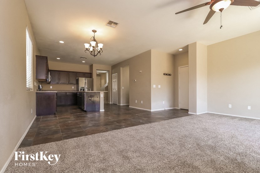 a empty living room and kitchen with a ceiling fan