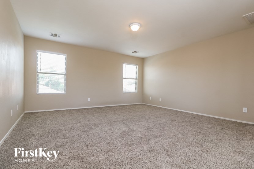 an empty living room with carpet and two windows