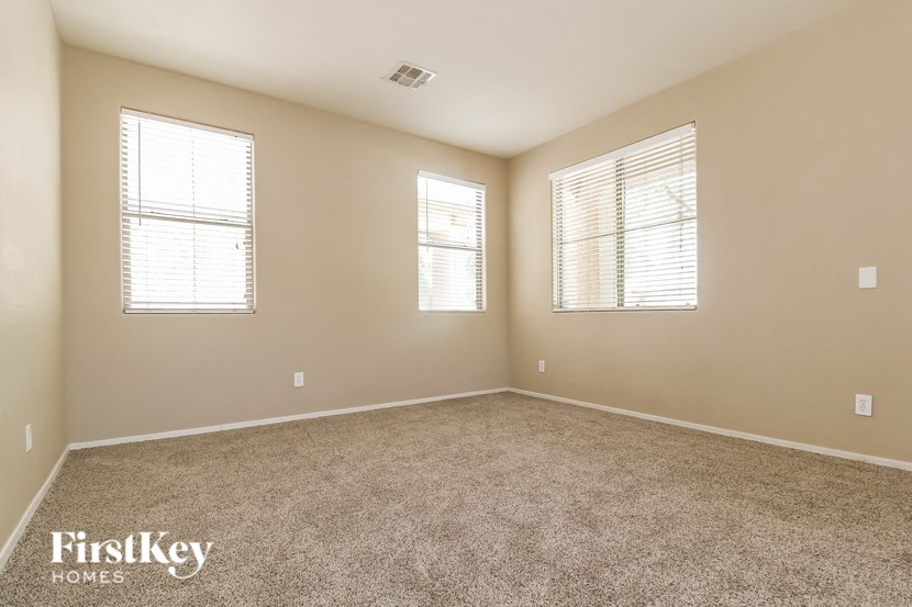 an empty room with three windows and carpet