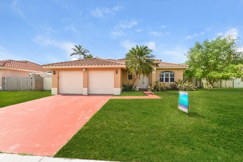 a house with a pink driveway and a palm tree
