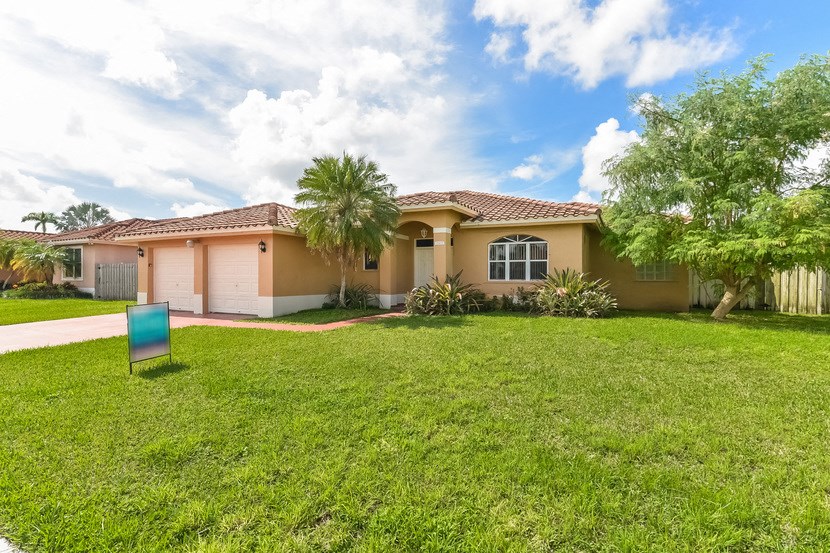a house with a lawn and palm tree in front of it