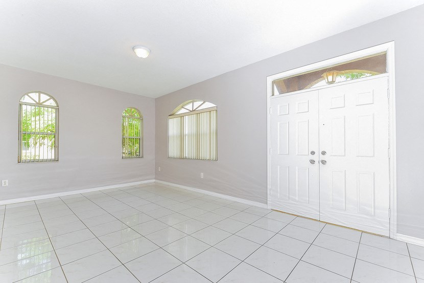 an empty room with a white tile floor and a white door