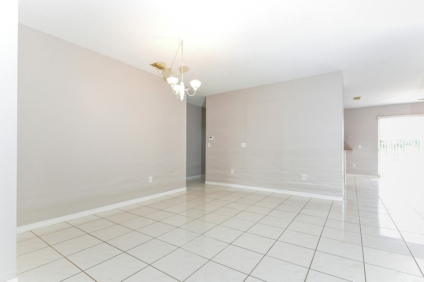 an empty living room with a white tiled floor and white walls