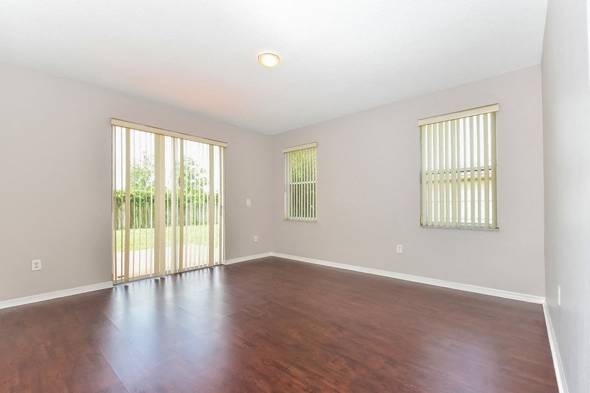 an empty living room with wood flooring and sliding glass doors