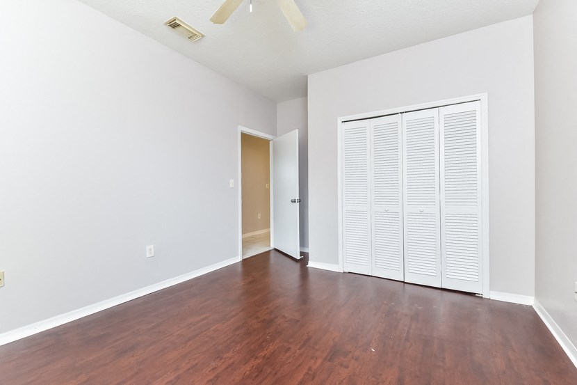 an empty living room with wood flooring and a large closet