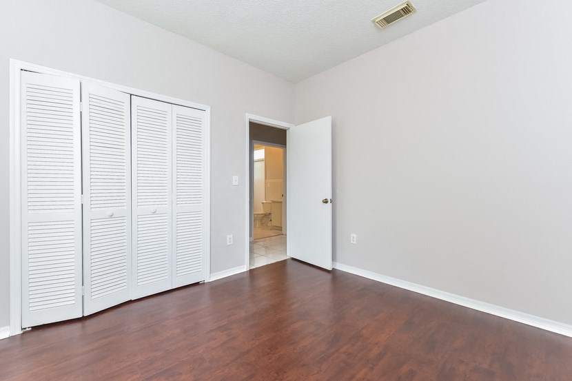 an empty living room with wood floors and white closet doors