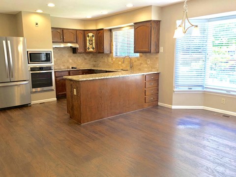 A kitchen with wooden cabinets and a stainless steel refrigerator.