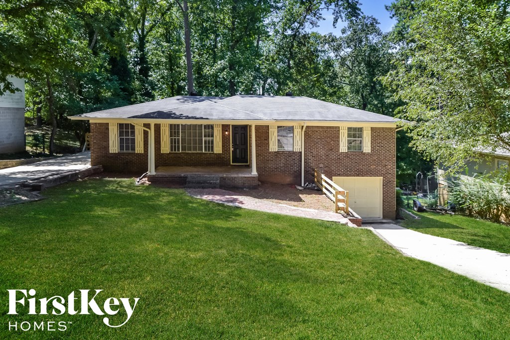 a small brick house with a porch and a lawn