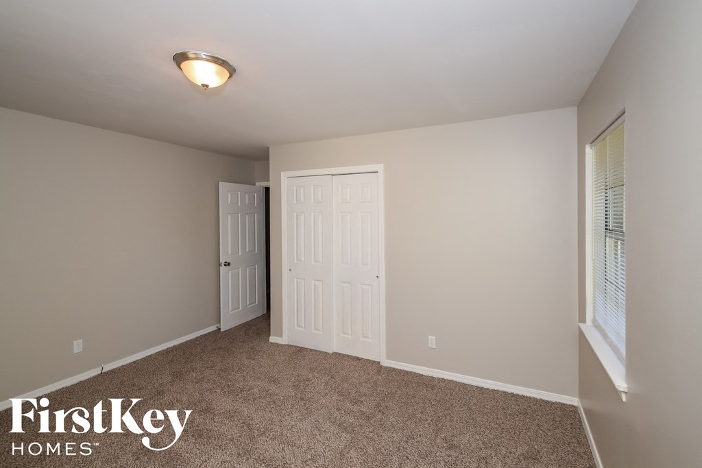 a bedroom with a carpeted floor and a door to a closet