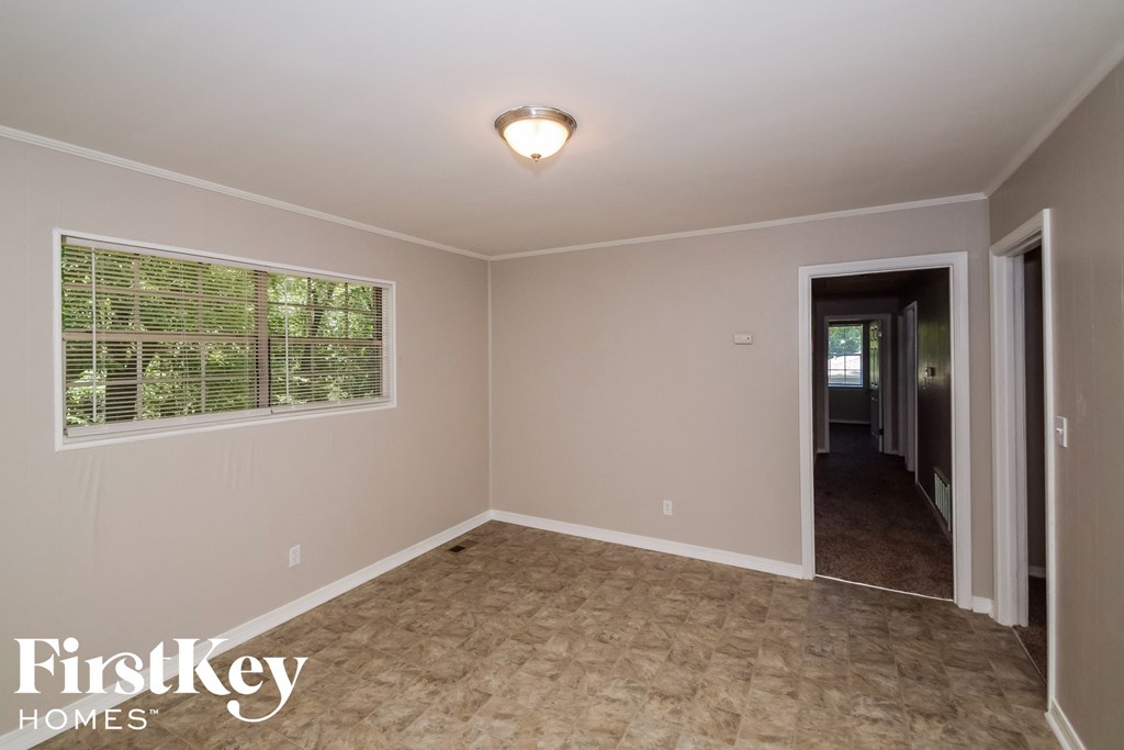 a empty living room with a large window and a door to a hallway
