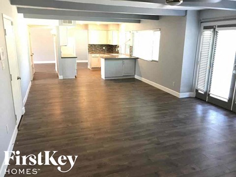 an empty living room and kitchen with wood floors