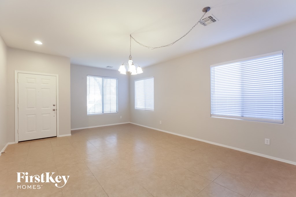 A spacious room with a door, two windows with blinds, and a light fixture on the ceiling.