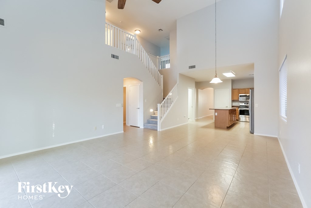 A spacious living room with a staircase and a kitchen in the background.