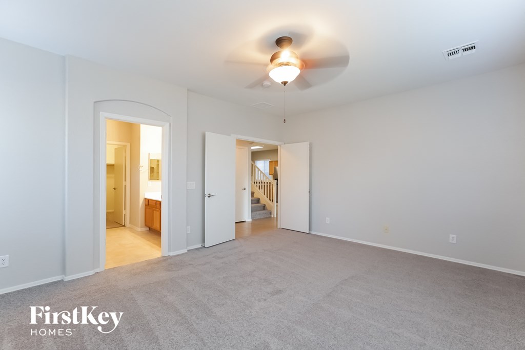 A spacious room with a fan and a carpeted floor.