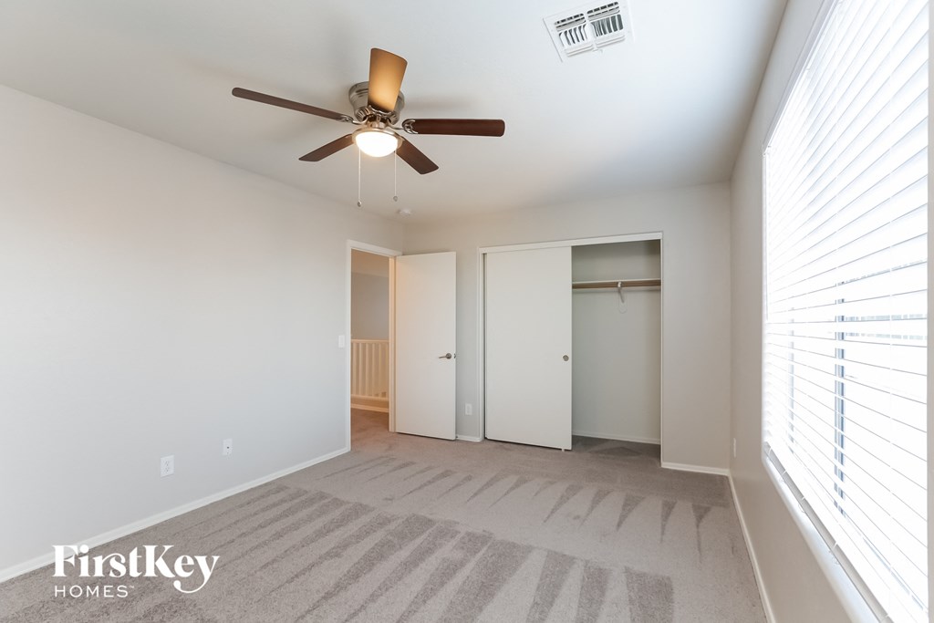 A room with a ceiling fan and a carpeted floor.