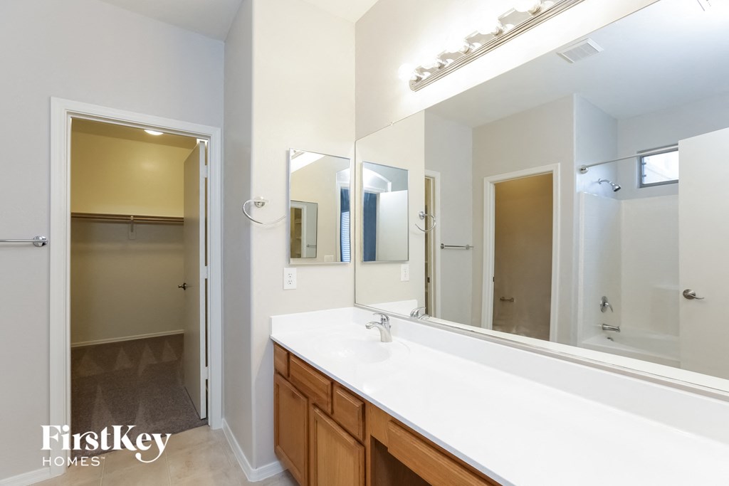 A bathroom with a sink, mirror, and a door.