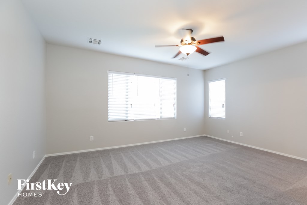A spacious room with a ceiling fan and carpeted floor.