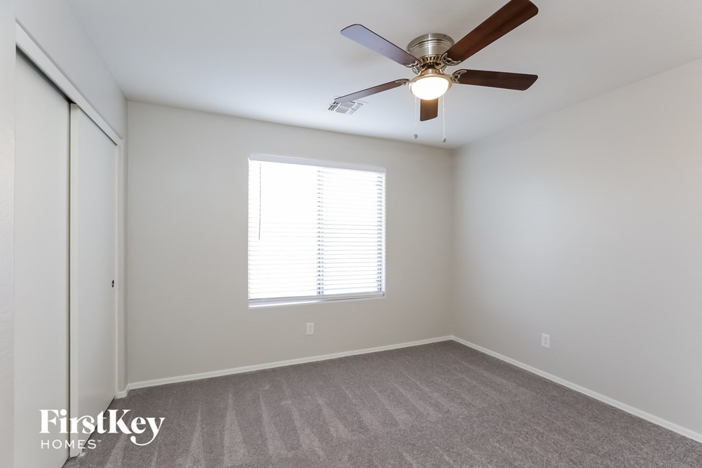 A room with a ceiling fan and a window with blinds.