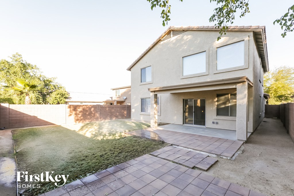 A modern house with a large front yard and a brick patio.