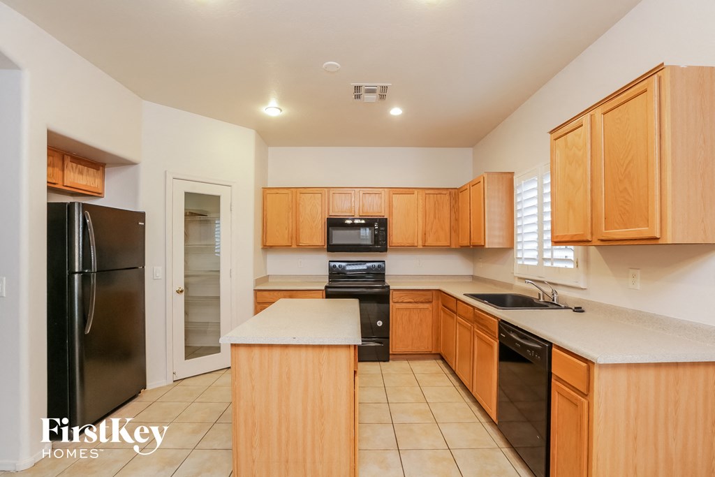 a kitchen with wood cabinets and black appliances and white countertops