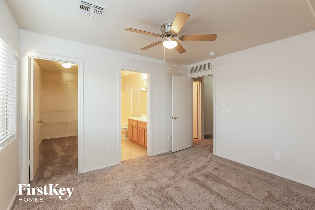 an empty living room with a ceiling fan and a bathroom
