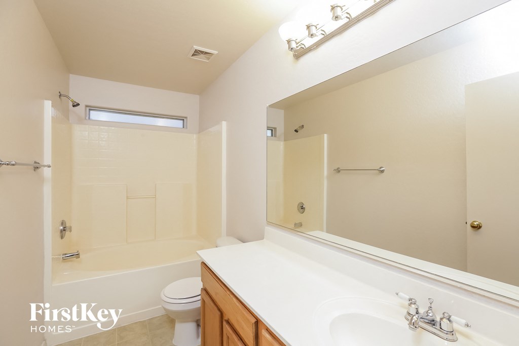 a white bathroom with a large mirror and a white toilet and sink