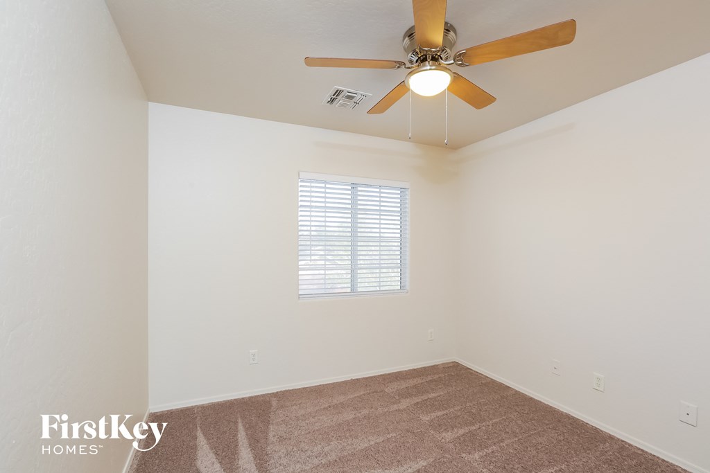 a living room with a ceiling fan and a carpet