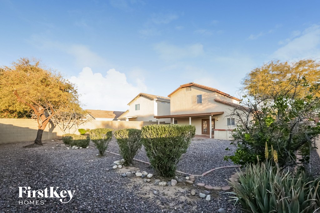 a house with a gravel driveway and a row of plants in front of it