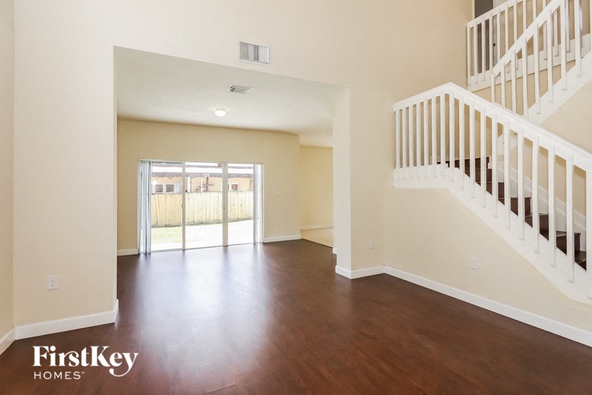 an empty living room with a staircase and a door to a balcony